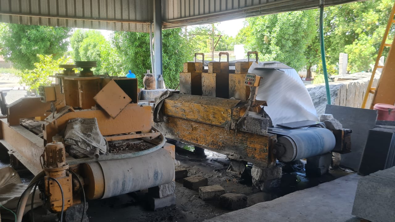 Granite cutting and polishing machine with a feed roller under a covered shed